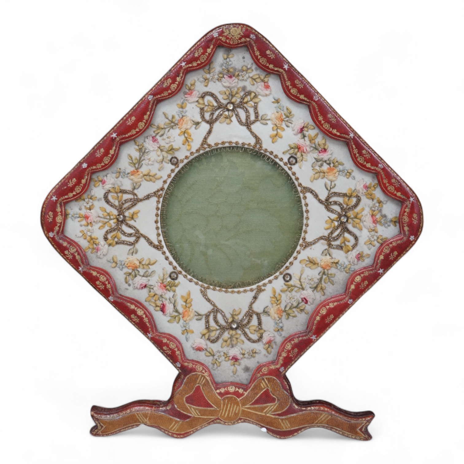 An Edwardian decorative stamped gilt leather photo frame, with bow to base and a floral patterned ribbon and sequin work front panel. 27.5cm high. Condition -good